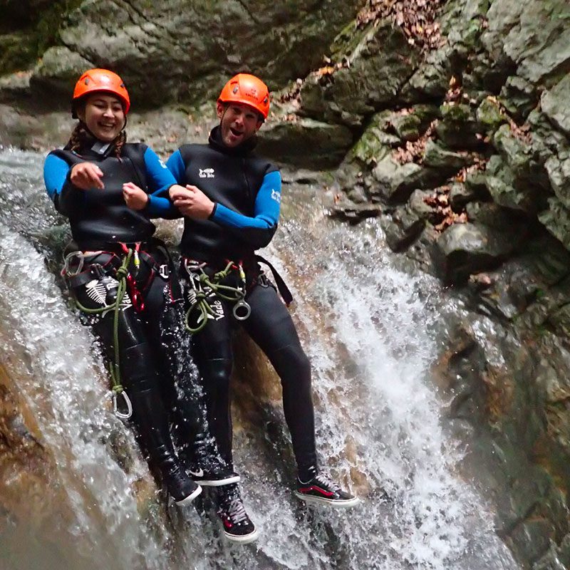 Glissage dans une chute d'eau sur le parcours de canyoning d'Angon