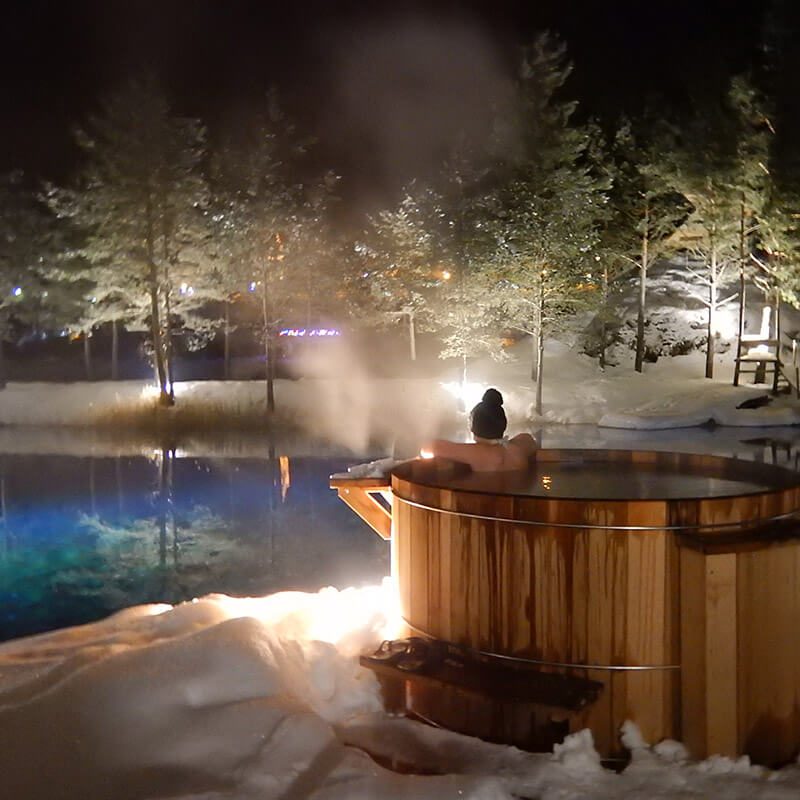 Femme dans un bain nordique bien chaud, face aux paysage enneigé