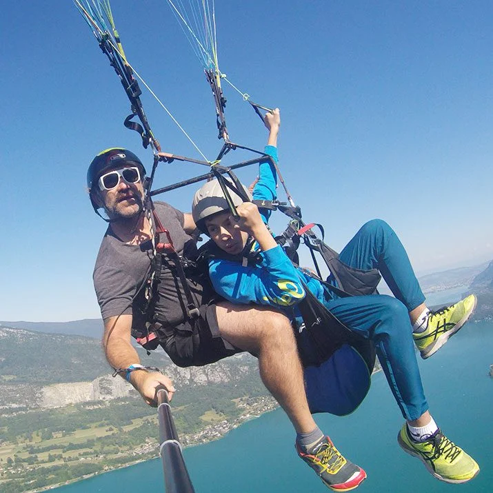 Enfant volant en parapente au dessus du lac d'Annecy, accompagné de son moniteur