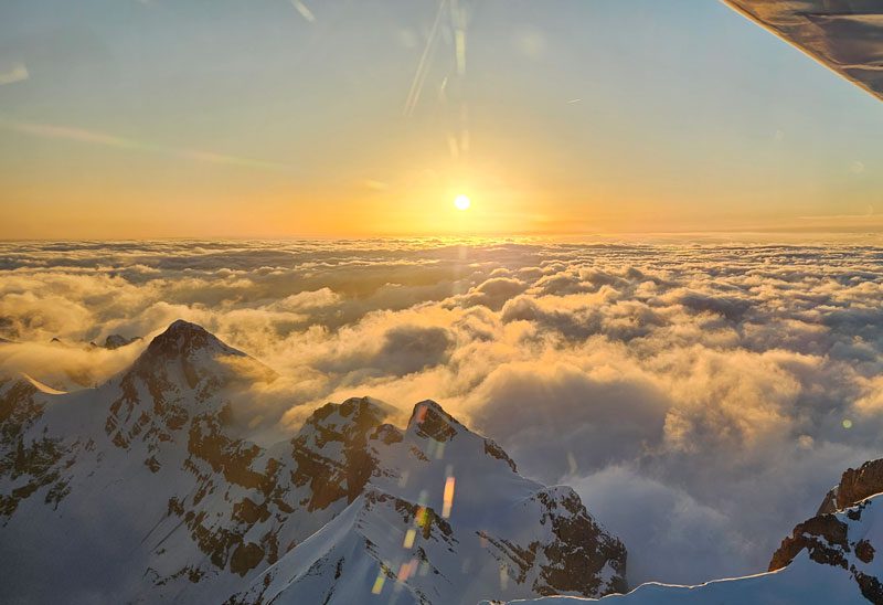 Vol en ULM au dessus des montagnes enneigées au couché du soleil